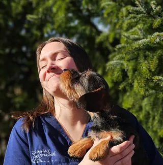 Smilende kvinne i blå veterinæruniform foran lys vegg.